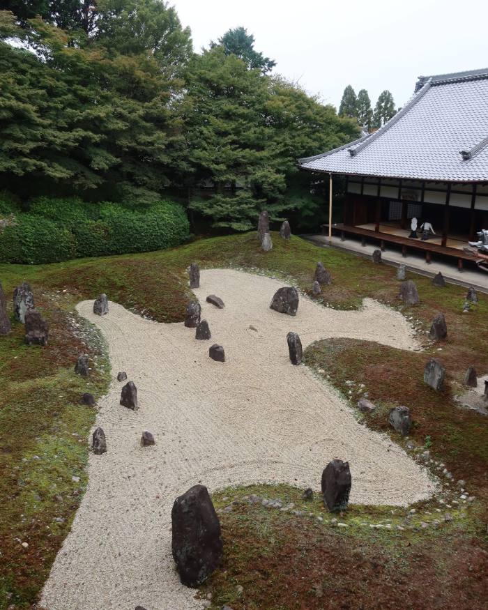 A raked gravel garden with stones beside a temple building