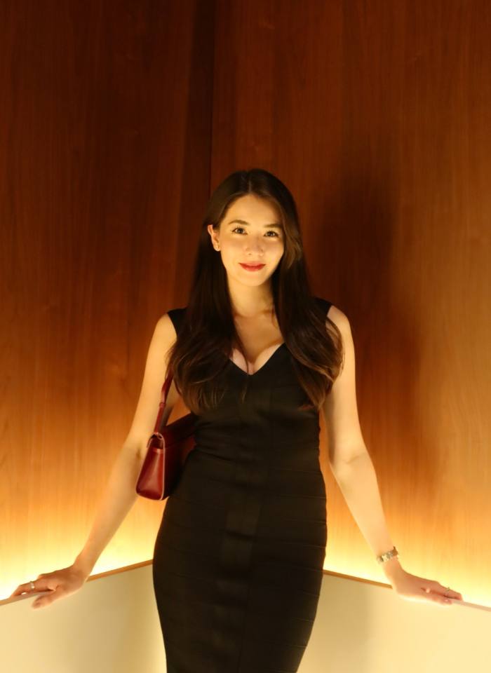 Erika in a black dress, standing in a warmly lit wooden corridor
